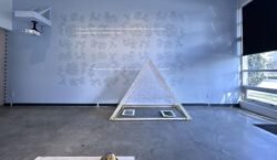 View of a memory with you exhibition looking west towards an installation of a delicate installation in front of a painted wall.
